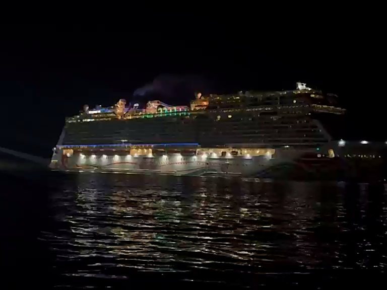 Crucero iluminado en el muelle de noche, visto desde el agua